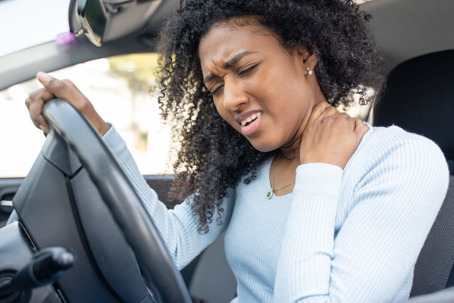 Women holding neck in pain in car
