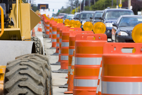 Orange construction barriers separate construction from the busy traffic