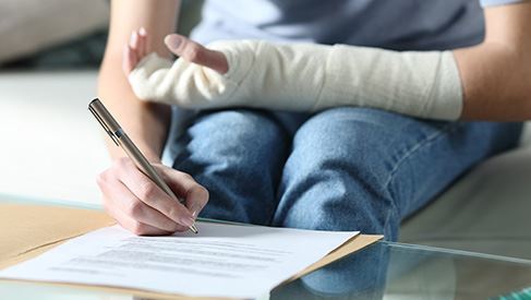 person with injured arm signing paper